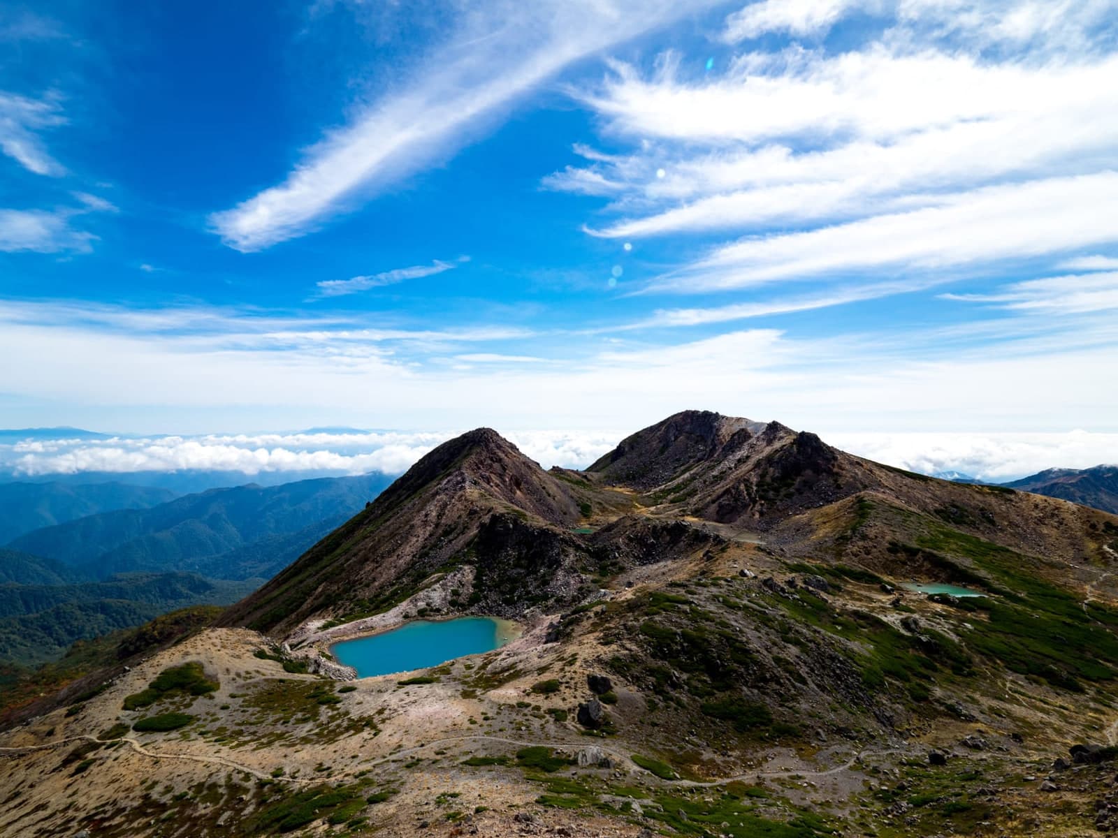 Cume do Hakusan com lagoa vulcânica acima do mar de nuvens